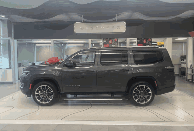 a gray suv with a red bow in front of a sign that says ' wagner '