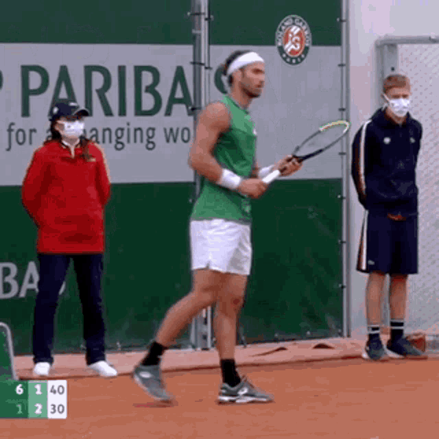 a man in a green tank top is holding a tennis racquet in front of a banner that says pariba