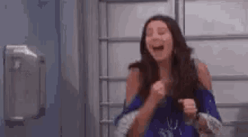 a woman is laughing and holding her fist up in the air .