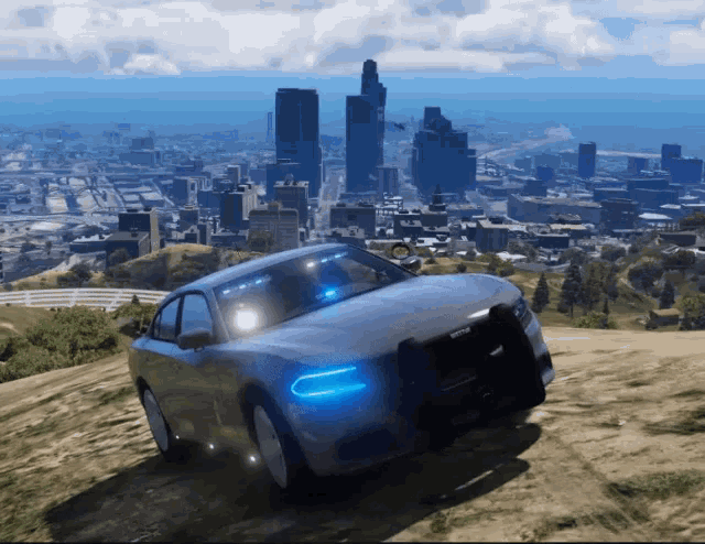 a police car is driving down a hill in front of a city skyline