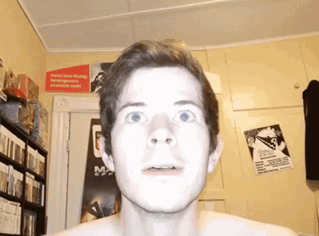 a shirtless man stands in front of a sign that says metal gear