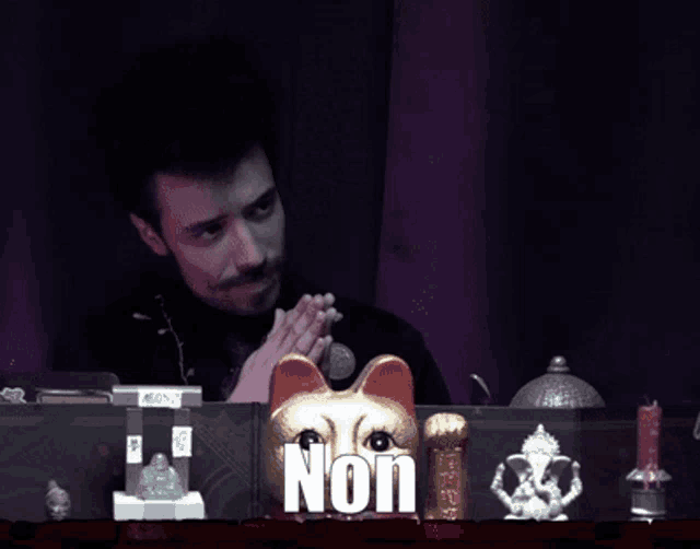 a man sitting at a desk with a statue of a cat and the word non on the bottom