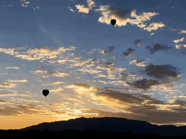 three hot air balloons flying in the sky at sunset