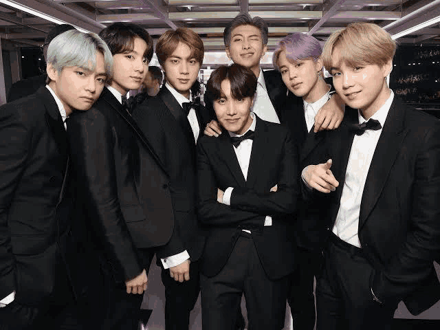 a group of young men wearing tuxedos and bow ties pose for a picture .