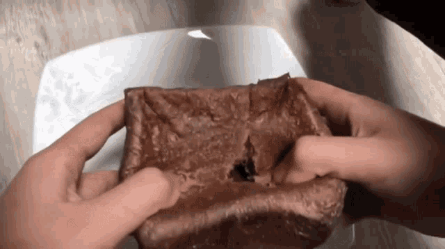 a person is holding a piece of chocolate cake with a hole in it