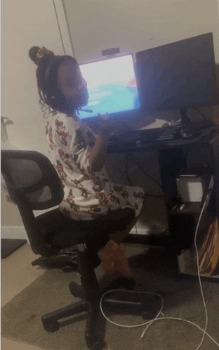 a woman sits in a chair in front of a computer with a mouse in her hand
