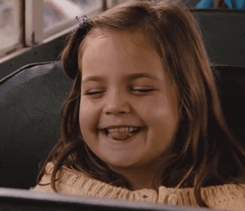 a little girl is sitting on a bus with her eyes closed and smiling