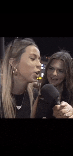 two women are talking into microphones and one of them is holding a microphone .