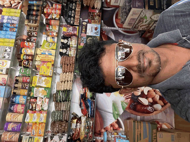 a man wearing sunglasses stands in front of a display of food items including a box that says wafer