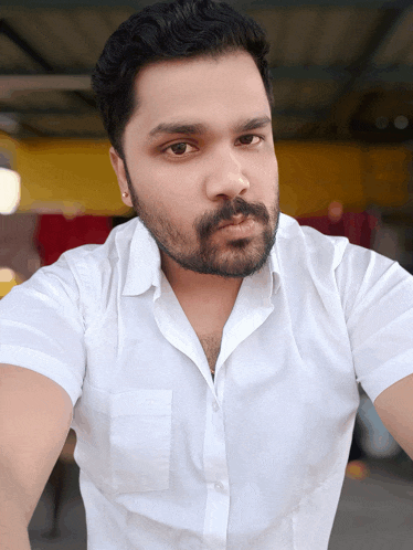 a man with a beard wearing a white shirt is looking at the camera