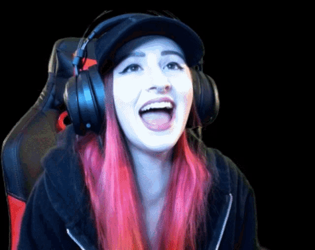 a woman with pink hair wearing headphones and a black hat