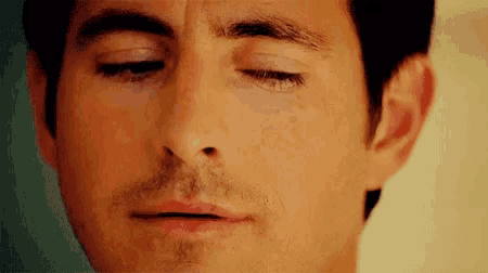a close up of a man 's face with his eyes closed and mouth open .