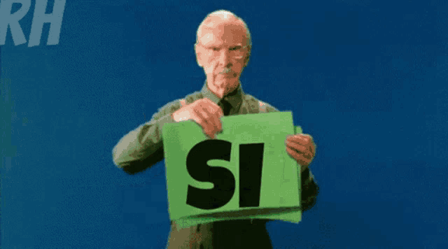 an elderly man holds a green sign that says si si