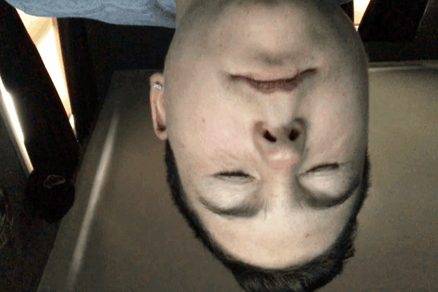 a man 's head is upside down with his eyes closed and his mouth open