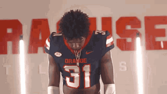 a football player with the number 31 on his jersey stands in front of a wall that says raise