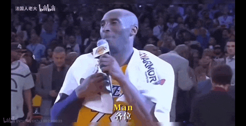 a man in a lakers jersey holds a microphone