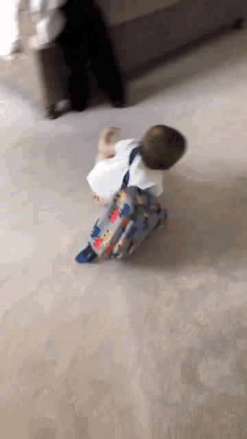 a baby with a backpack is crawling on the floor .
