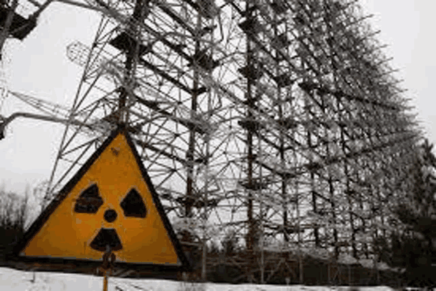 a yellow and black sign with a radioactive symbol on it is in front of a very tall building .