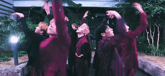 a group of young men are standing next to each other with their arms in the air and dancing .