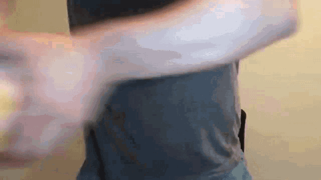 a man in a grey shirt is holding a white object in his hands .