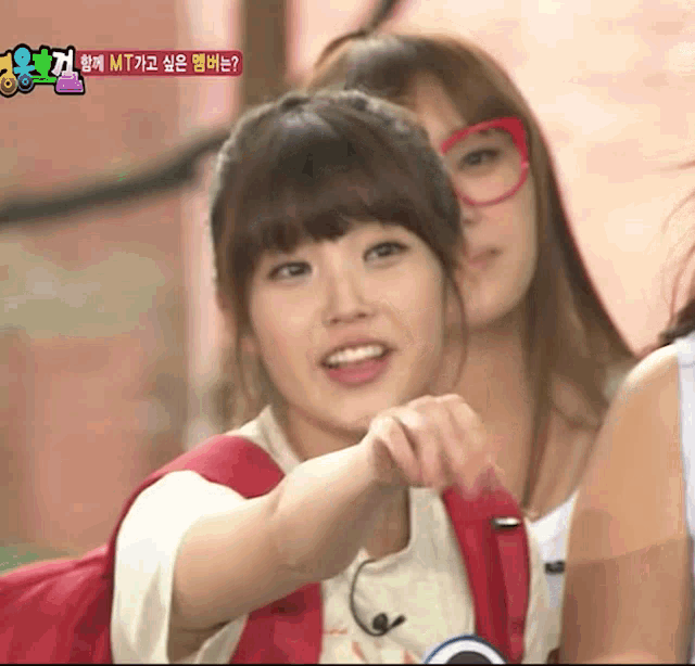 a girl with glasses and a red backpack is pointing at the camera