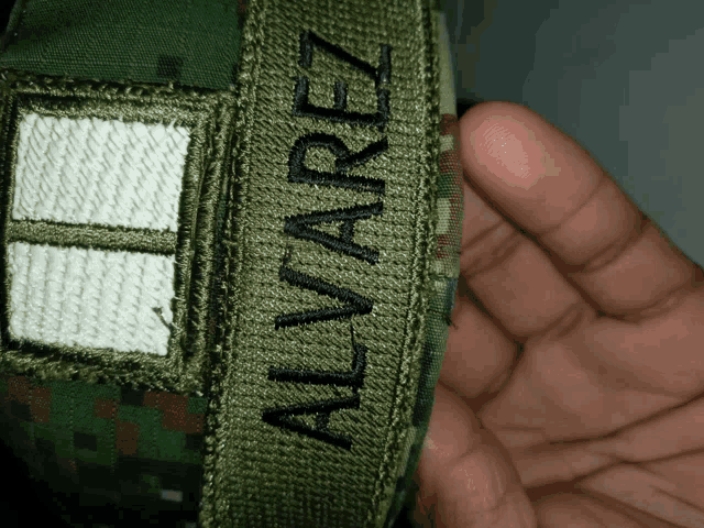 a person holding a military uniform with the name alvarez on it