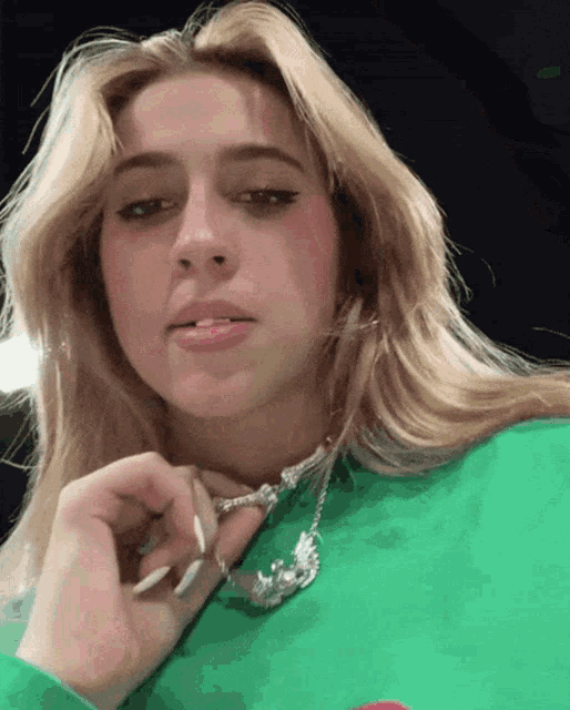 a close up of a woman wearing a green shirt and a silver necklace