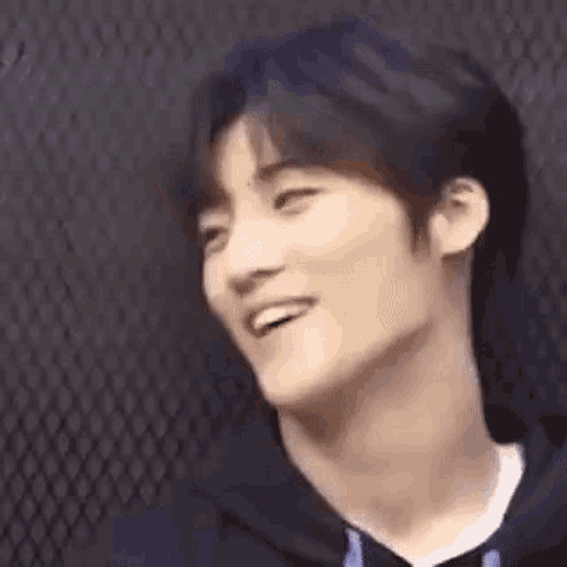 a young man is smiling in front of a fence .