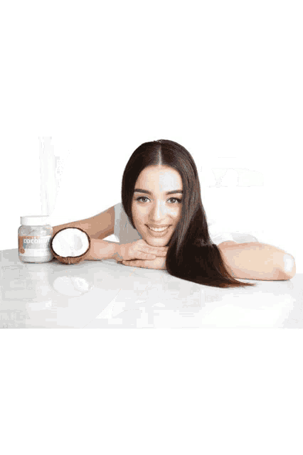 a woman wearing a plastic cap sits in front of a counter with a hair dryer and a bottle of vitamins on it