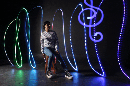 a woman sits on a stool in front of a wall with a treble clef and a swirl of lights