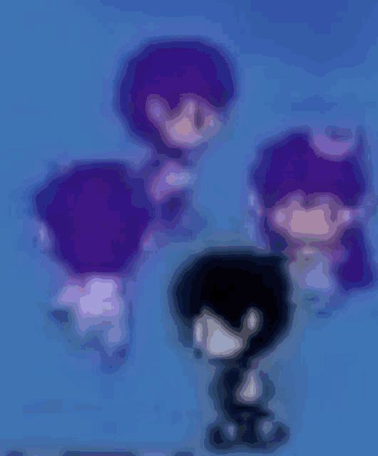 a blurry picture of a boy standing in front of a group of purple characters .