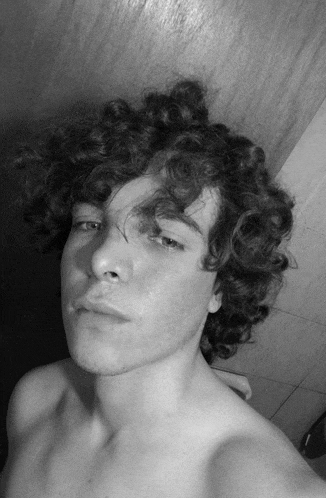 a young man with curly hair takes a selfie