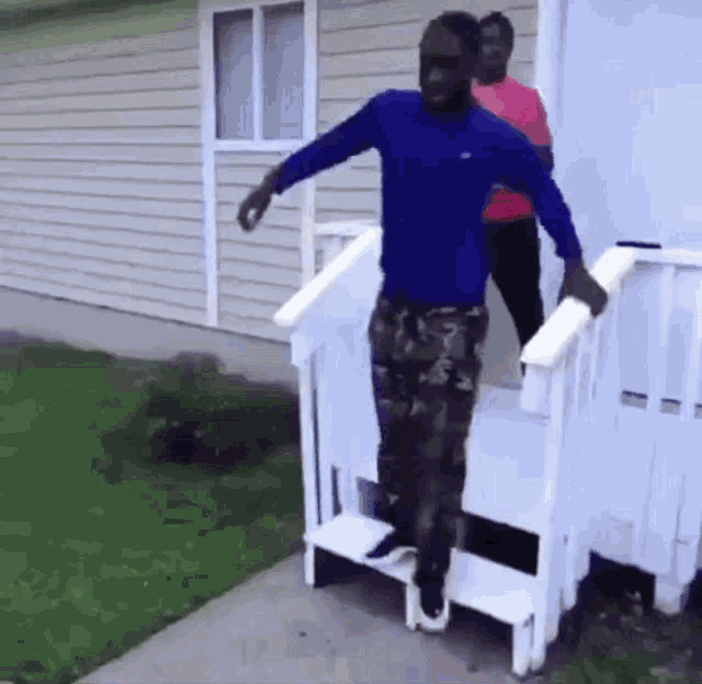 a man in a blue shirt is standing on a set of stairs in front of a house