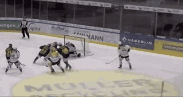 a hockey game is being played on a rink with a muller logo in the background .