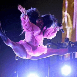 a woman in a pink dress is flying through the air while singing into a microphone .