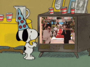 snoopy wearing a party hat looks at a tv screen