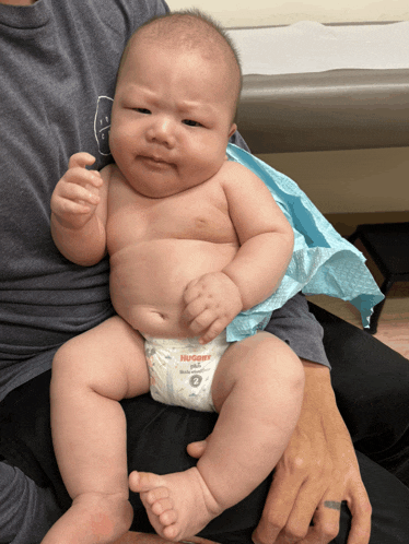 a baby wearing a huggies diaper is being held by a person