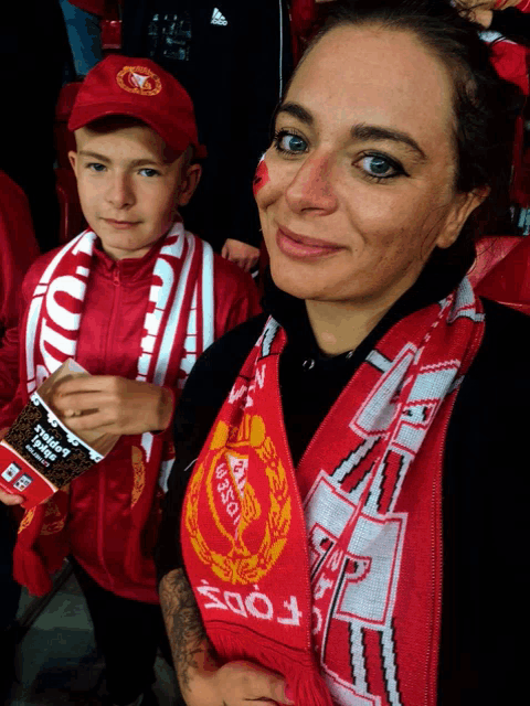 a woman wearing a red scarf with the word ford on it stands next to a boy