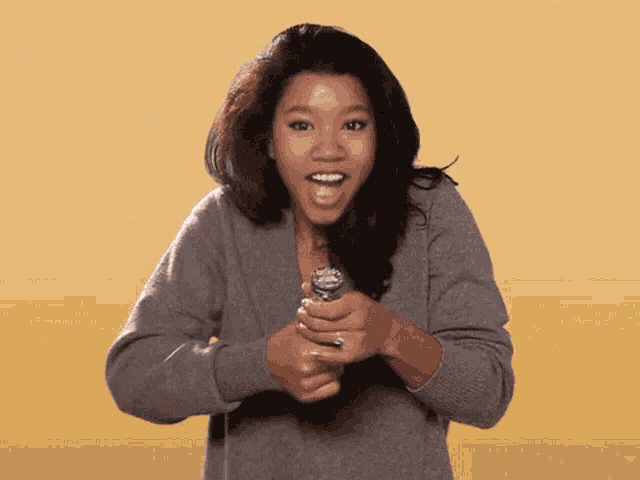 a woman in a grey sweater is holding a bottle opener