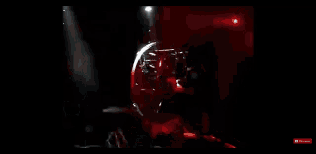 a man is riding a bicycle on a stage in a dark room with red lights .