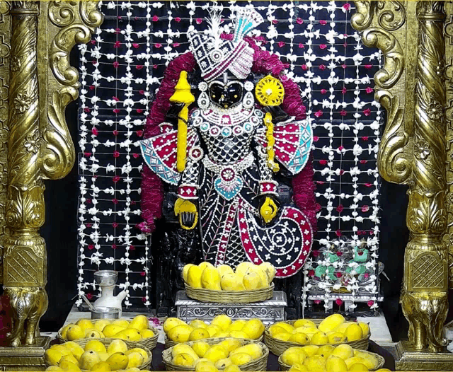 a statue of a deity is surrounded by baskets of fruit