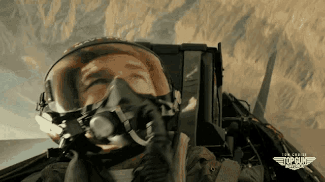 a man wearing a helmet and goggles is flying in a top gun plane