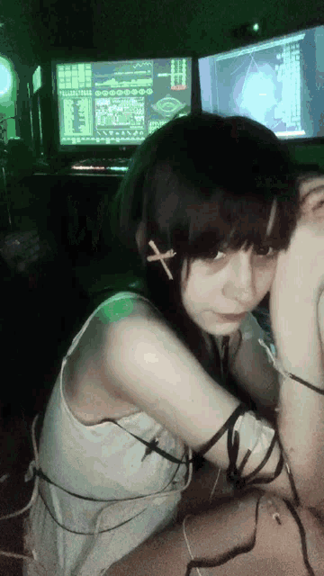 a girl with a cross in her hair sits in front of a computer screen