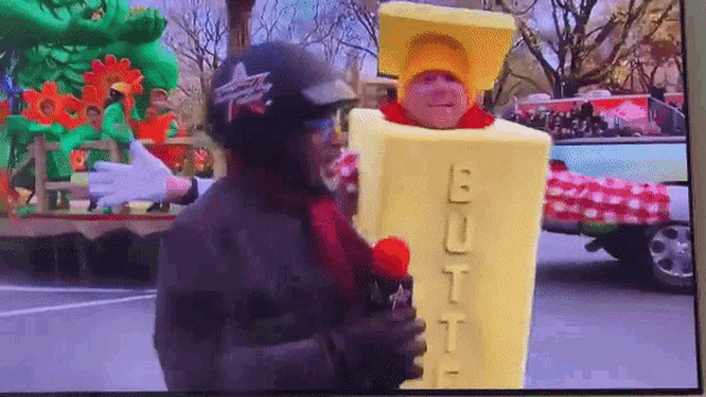 a man in a butter costume is interviewing another man