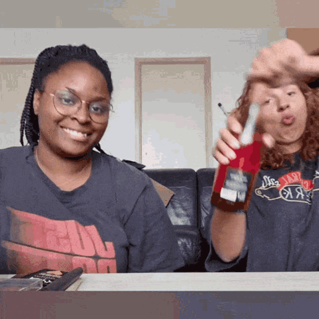 a woman holding a bottle of coca cola next to another woman wearing a shirt that says ' a ' on it