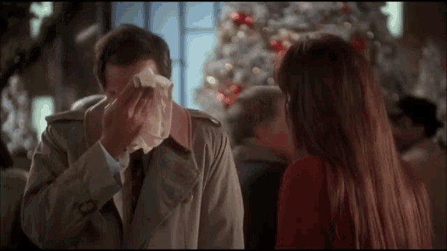 a man wipes his nose with a napkin in front of a woman