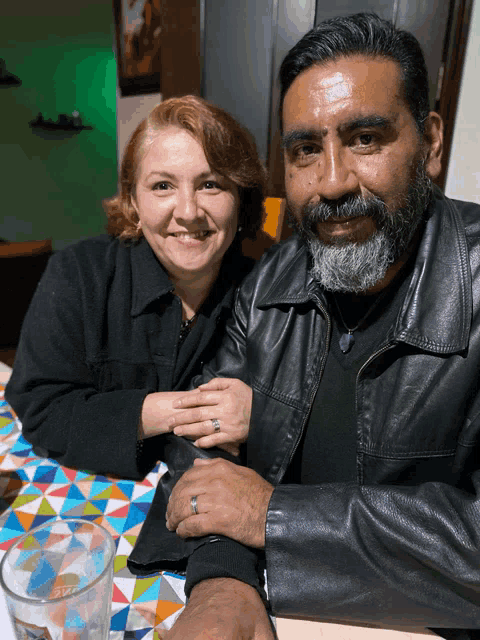 a man and a woman are posing for a picture and the woman is wearing a wedding ring