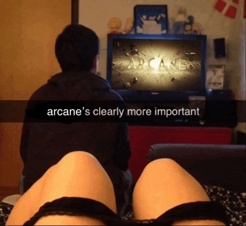 a man and a woman watching arcane on a television