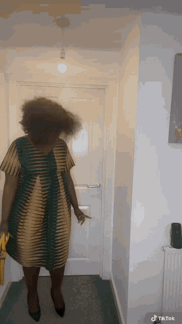 a woman in a striped dress is standing in a hallway