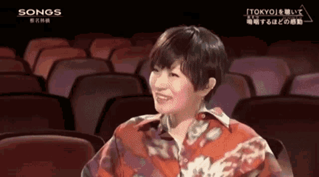 a woman sits in an auditorium with the words songs on the bottom left